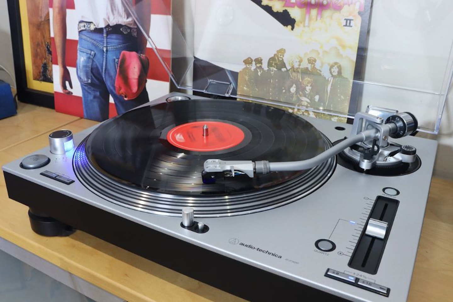 Audio-Technica LP140XPSVEUK Professional Manual Turntable on a unit next to LPs playing a record